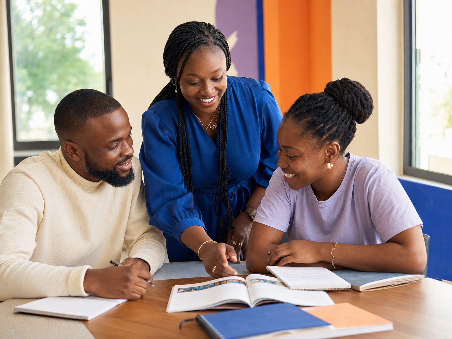 A French instructor coaching two adult learners in a bright Lagos classroom